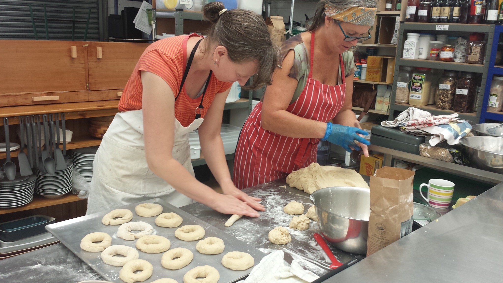 2 cooks laying rings of bagel dough onto a baking tray